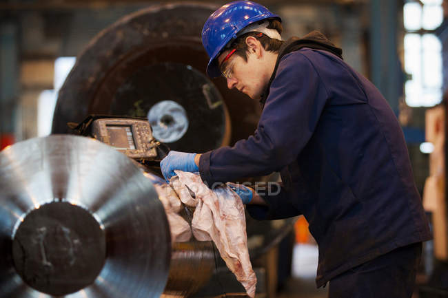 Worker cleaning metal in steel forge — Stock Photo