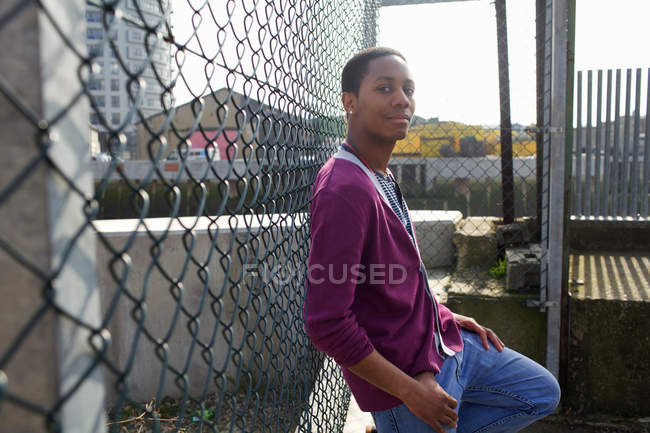Smiling man leaning against fence — Stock Photo