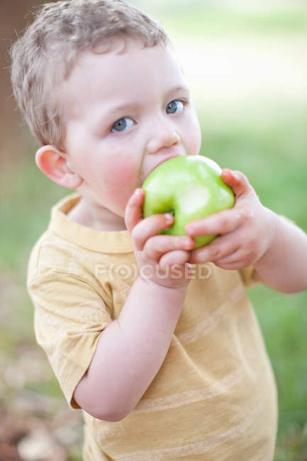 Garçon manger de la pomme à l'extérieur — Photo de stock