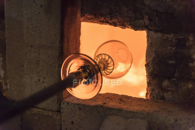 Glassblower heating glass in furnace — Stock Photo