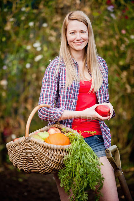 Жінка, що збирає овочі в саду, фокус на передньому плані — стокове фото
