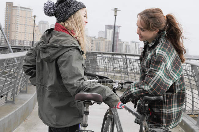 2 молоді жінки спілкуються з штовхаючими велосипедами — стокове фото