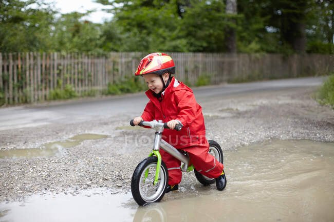 Усміхнений хлопчик їде на велосипеді в калюжах — стокове фото