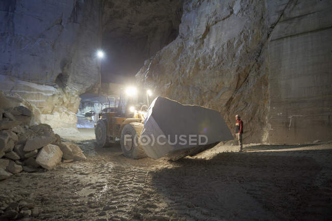 Worker and excavator in marble quarry — Stock Photo