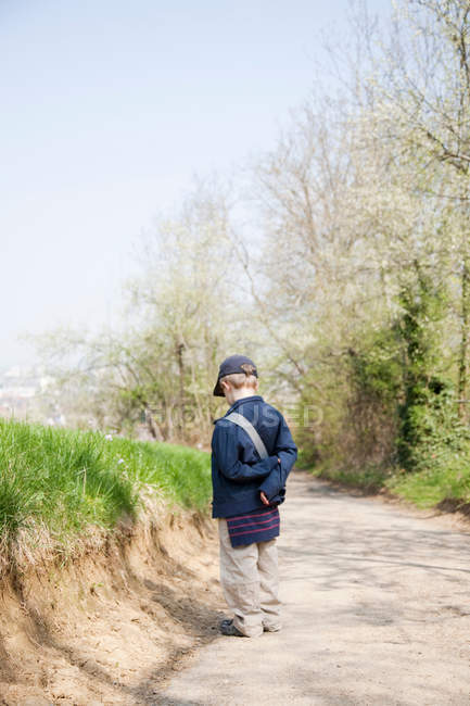 Мальчик в кепке на грунтовой дороге — стоковое фото