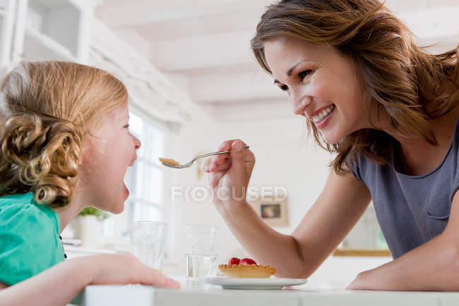 Donna che nutre figlia colazione — Foto stock