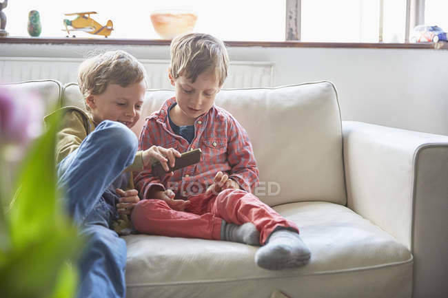 Два младших брата используют смартфон дома — стоковое фото