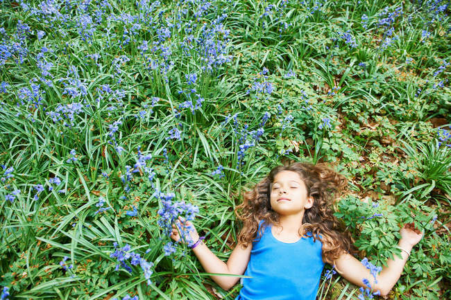 Menina que põe no campo de flores — Fotografia de Stock
