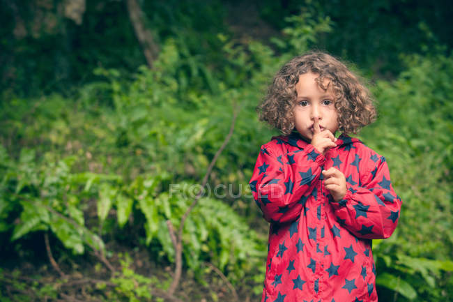 Девушка держит палец над губами в лесу — стоковое фото