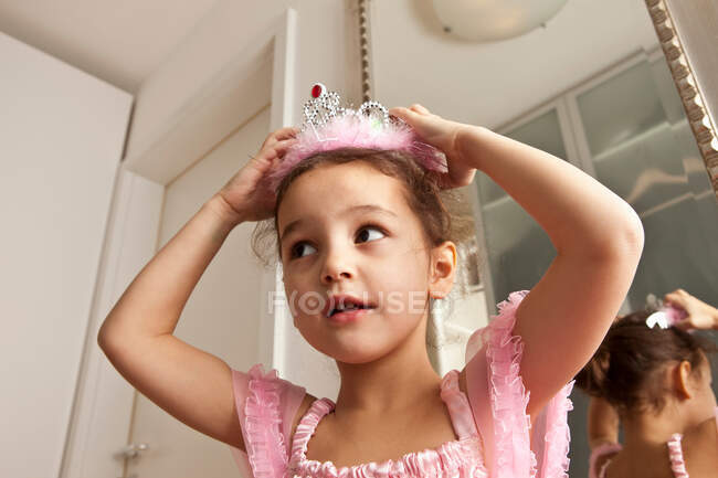 Chica poniendo corona en su cabeza - foto de stock