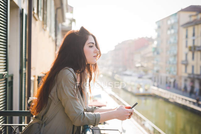 Ritratto di bella giovane donna che guarda dal balcone sul lungomare — Foto stock