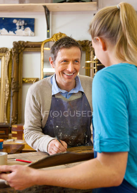Carpenter talking to woman in shop, selective focus — Stock Photo