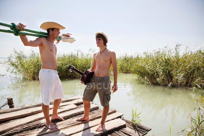Two men chatting in the sun lakeside — Stock Photo
