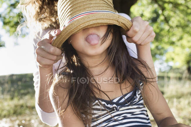 Зріла жінка вкриває очі солом'яним капелюхом у парку — стокове фото