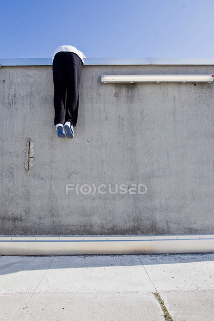 Человек взбирается на стену на городской улице — стоковое фото