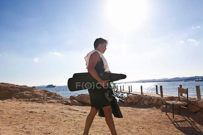 Snorkeler carrying fins on sandy beach — Stock Photo