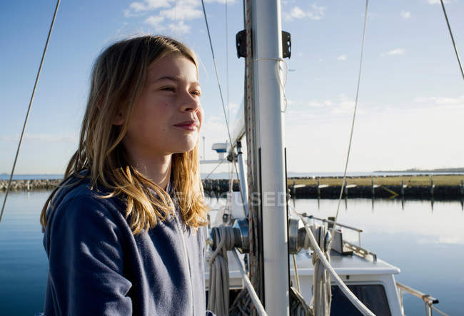 Girl standing on boat in harbor — Stock Photo