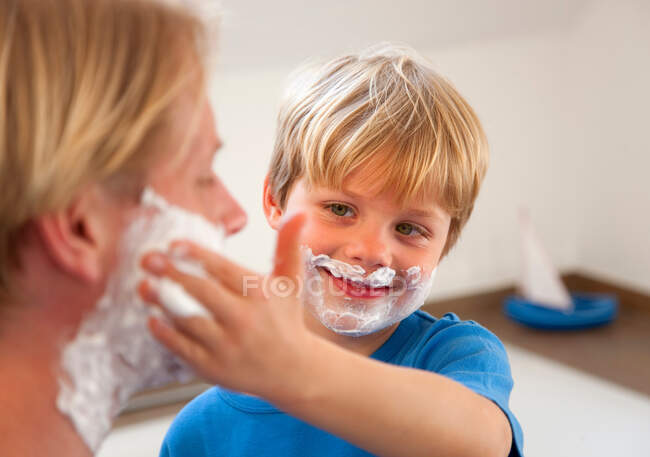 Padre e hijo aplicando crema de afeitar - foto de stock