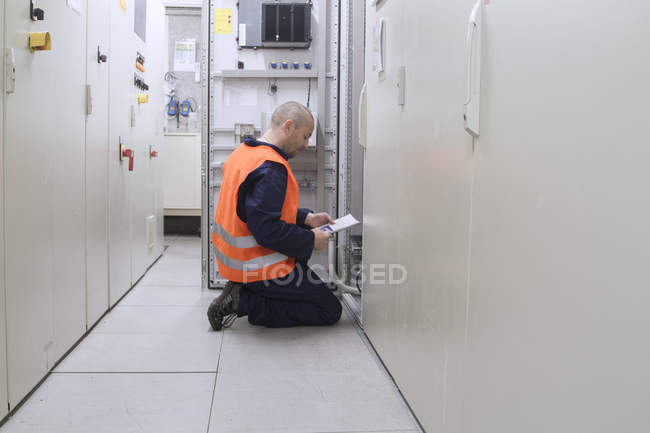 Technician reading paperwork in power station control room — Stock Photo