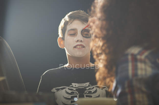 Mother painting son skeleton face for Halloween — Stock Photo