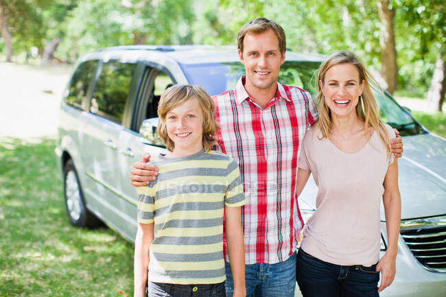 Familia sonriendo juntos en coche - foto de stock