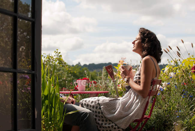Mujer en balcón beber té - foto de stock
