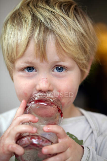 Ritratto del ragazzo che mangia marmellata dal barattolo — Foto stock