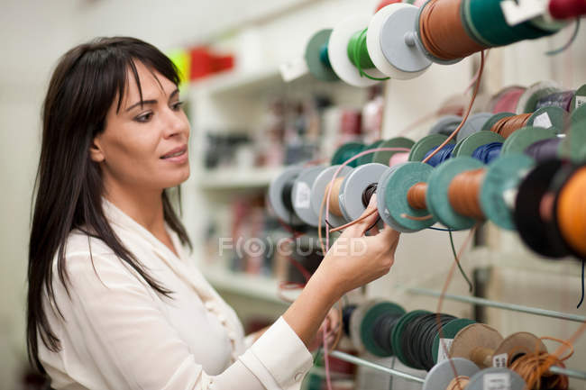 Жінка дивиться на кульки нитки в магазині — стокове фото