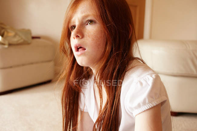 Girl sitting on living room floor — Stock Photo