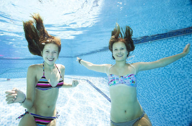 Two teenage girls swimming underwater in swimming pool — Stock Photo