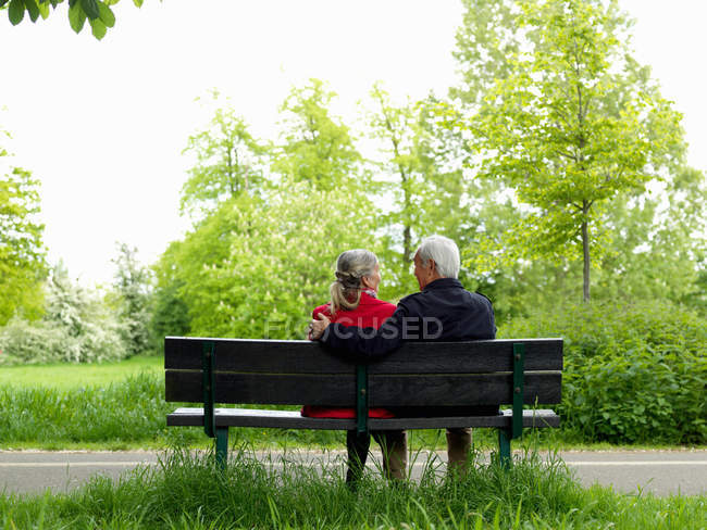 Older couple sitting on park bench — Stock Photo