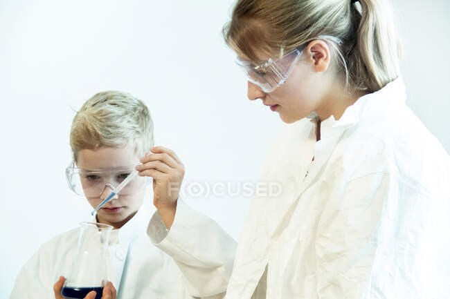 Hermano y hermana usando gafas de seguridad haciendo experimento científico - foto de stock