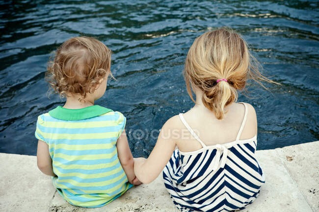 Meninas sentadas na borda da piscina — Fotografia de Stock