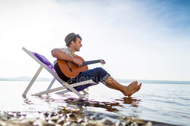 Man relaxing in lawn chair in creek — Stock Photo