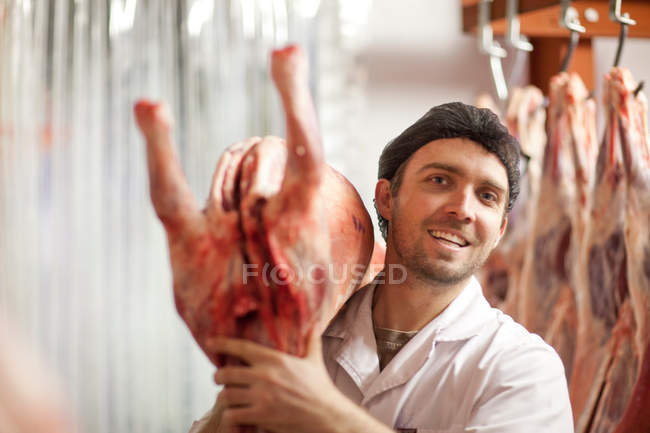 Carniceiro segurando carcaça sobre ombro — Fotografia de Stock