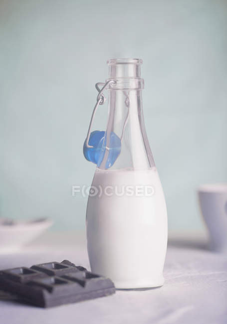 Botella abierta de leche y barra de chocolate - foto de stock