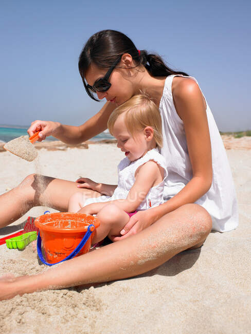 Mujer y niño sonriente en la playa - foto de stock