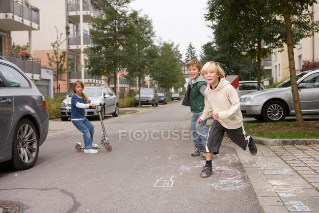 Niños jugando en la calle suburbana - foto de stock