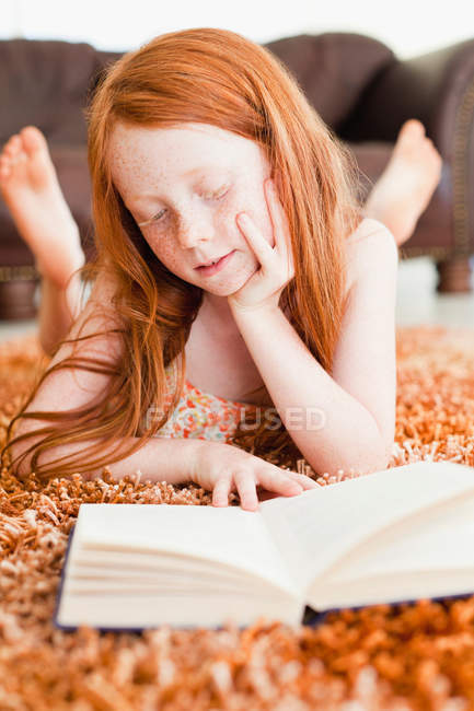 Chica leyendo en el piso de la sala - foto de stock