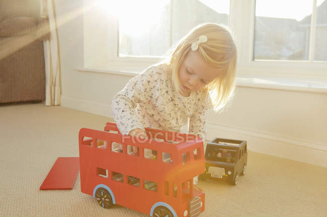 Fille jouer avec jouet bus sur le sol — Photo de stock