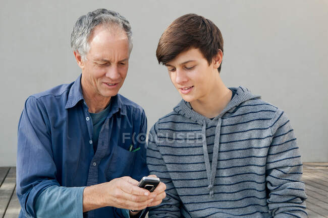 Father and son using cell phone together — Stock Photo