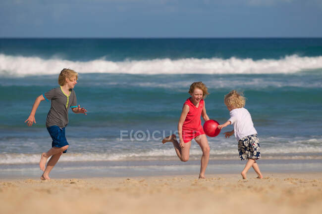 Crianças brincando com bola vermelha na praia — Fotografia de Stock