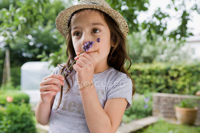 Girl smelling flower outdoors — Stock Photo