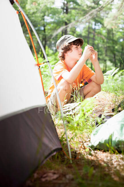 Boy sitting by tent at campsite — Stock Photo