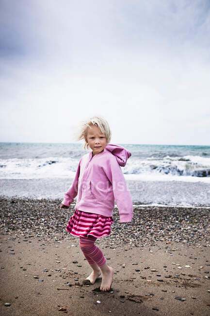 Girl walking barefoot on the beach — Stock Photo