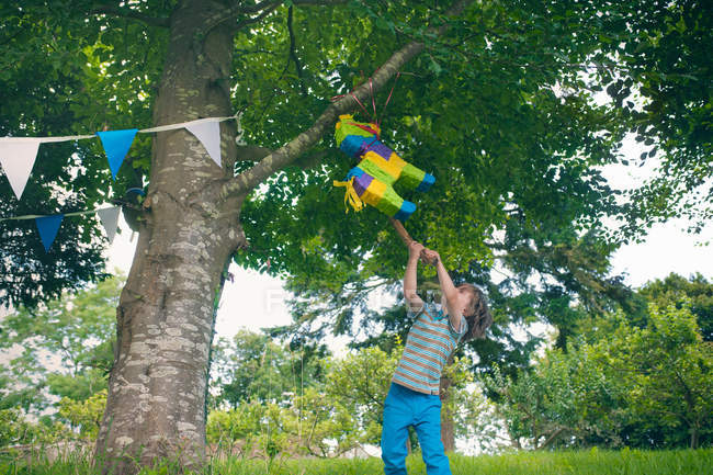 Menino balançando em pinata na festa — Fotografia de Stock