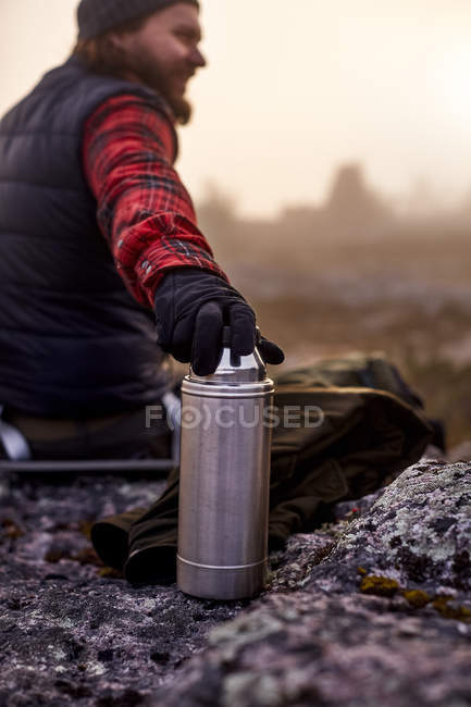 Male hiker sitting with coffee flask at travel — Stock Photo
