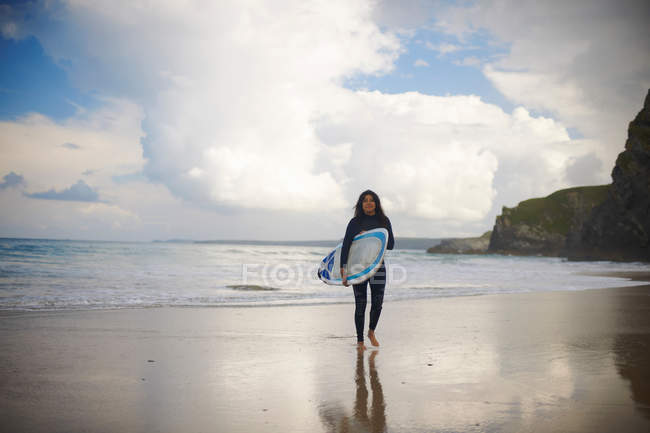 Surfer carrying board on beach — Stock Photo