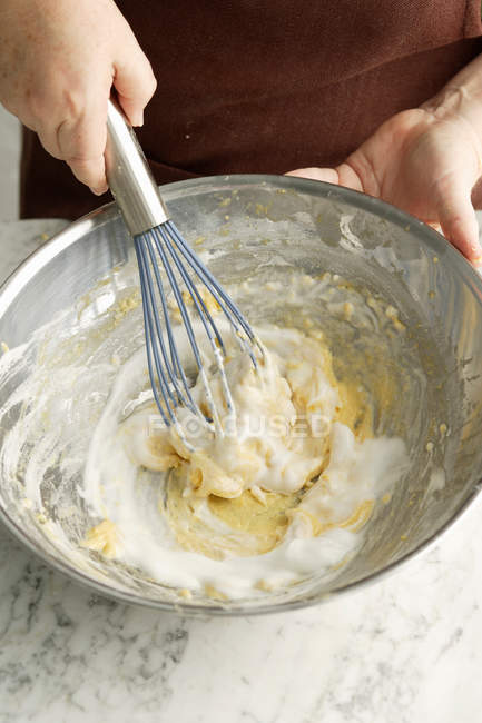 Female hands whisking dough in bowl — Stock Photo