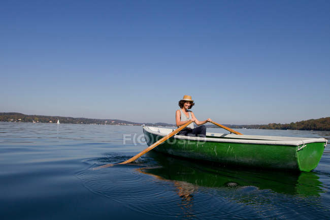 Жінка веслує на човні в нерухомому озері — стокове фото